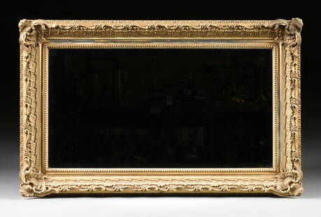 AN ANTIQUE ROCOCO STYLE PARCEL GILT AND CARVED WOOD: AN ANTIQUE ROCOCO STYLE PARCEL GILT AND CARVED WOOD MIRROR, LATE 19TH/EARLY 20TH CENTURY, the later rectangular beveled mirror glass panel enclosed by a conforming frame with beaded trim and stylized