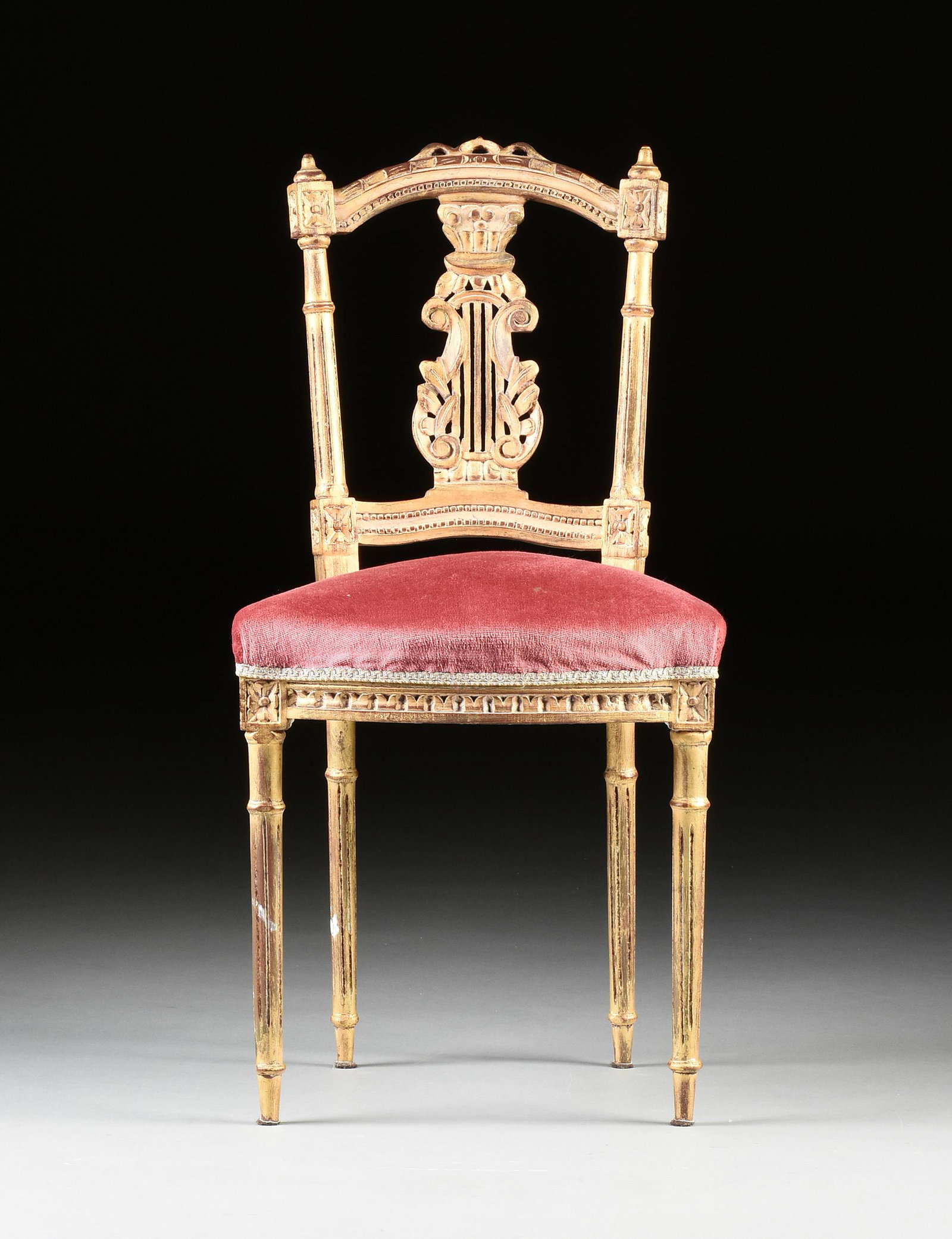 AN ITALIAN NEOCLASSICAL STYLE GILT BEECH MUSIC ROOM: AN ITALIAN NEOCLASSICAL STYLE GILT BEECH MUSIC ROOM CHAIR, FIRST HALF 20TH CENTURY, the arched crest rail over a vertical splat carved with a Corinthian style capital and pierced lyre, within ring tur