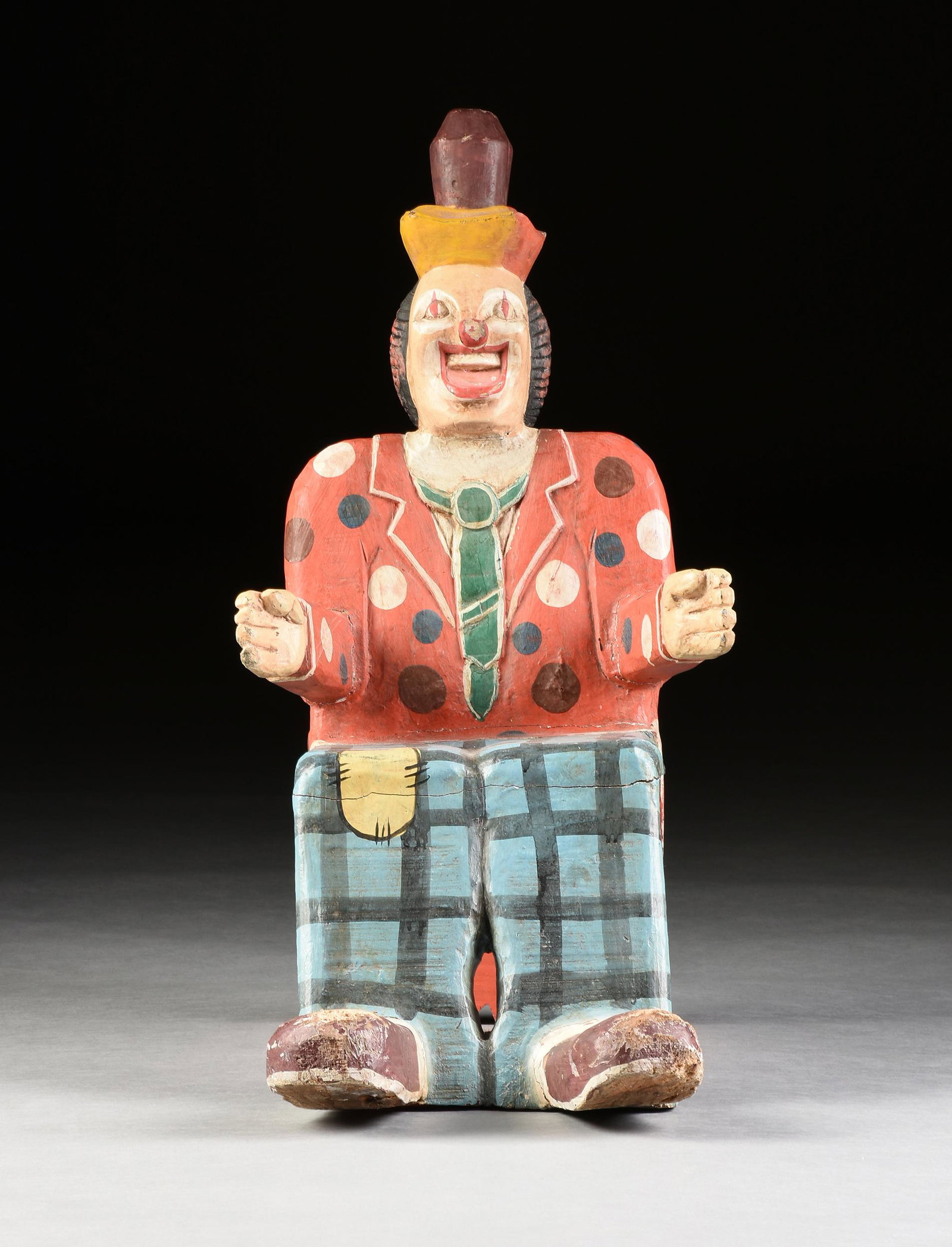 A VINTAGE FOLK ART POLYCHROME HAND CARVED CHILD'S CLOWN: A VINTAGE FOLK ART POLYCHROME HAND CARVED CHILD'S CLOWN CHAIR, PROBABLY AMERICAN, LAST HALF 20TH CENTURY, in the form of a hobo or tramp clown, a maroon coned, red, green and yellow hat, over a red no