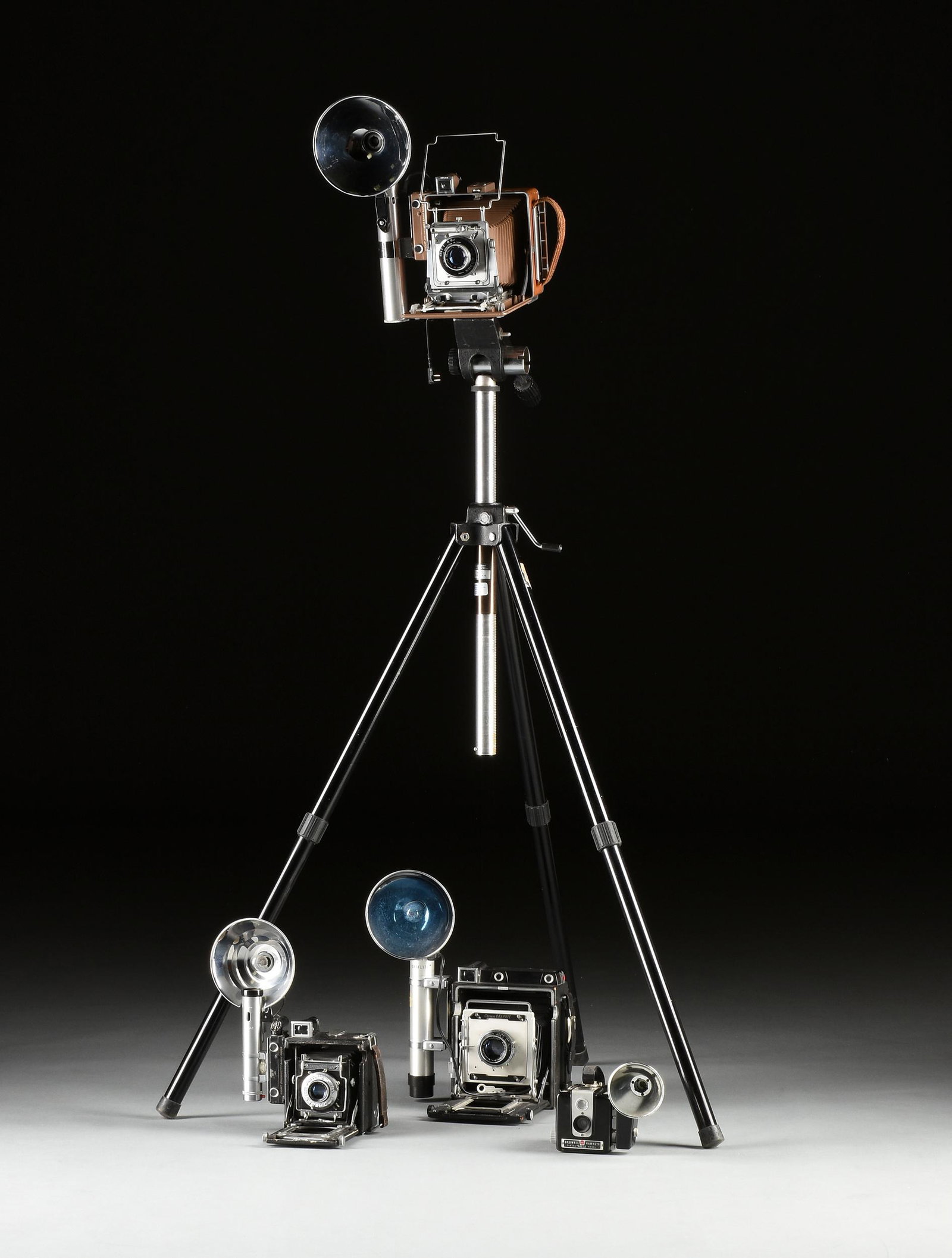A GROUP OF FOUR AMERICAN CAMERAS WITH FLASH AND TRIPOD: A GROUP OF FOUR AMERICAN CAMERAS WITH FLASH AND TRIPOD ATTACHMENTS, MID 20TH CENTURY, smallest to largest, a Brownie Hawkeye Camera Flash Model, with Kodalite Midget Flasholder attachment, height: 5 1