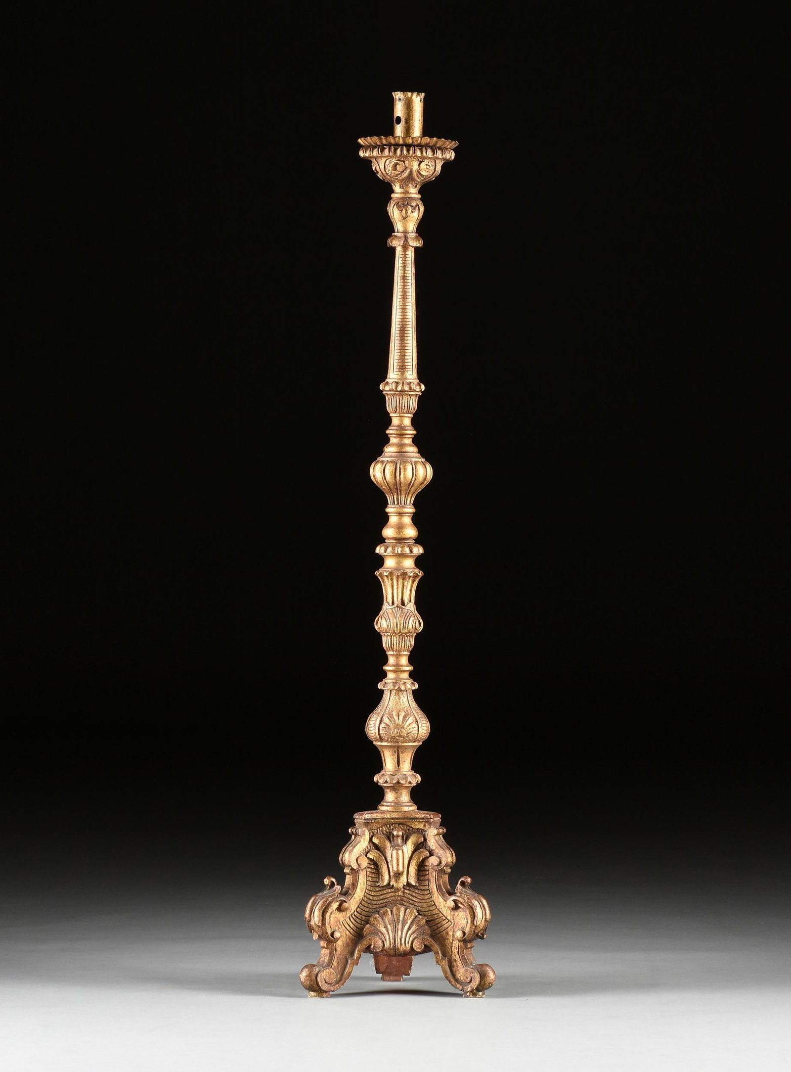 AN ITALIAN RENAISSANCE REVIVAL STYLE GILTWOOD FLOOR: AN ITALIAN RENAISSANCE REVIVAL STYLE GILTWOOD FLOOR CANDLESTICK, 19TH/20TH CENTURY, the ruffled candle cup and pie tin style bobÃ¨che over a sell and petal carved top on a reeded, tapered support ov
