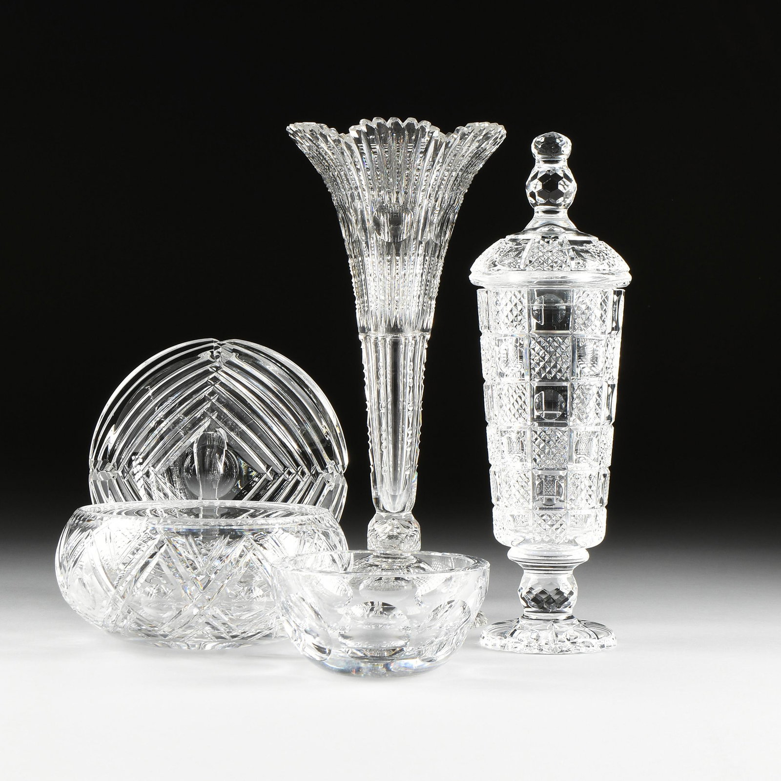 A GROUP OF FIVE CLEAR CRYSTAL VESSELS, AMERICAN AND: A GROUP OF FIVE CLEAR CRYSTAL VESSELS, AMERICAN AND CONTINENTAL, comprising a Josef Riedel cut clear crystal ashtray, the circular form item with tapering stepped bevel cuts to the sides centering an 