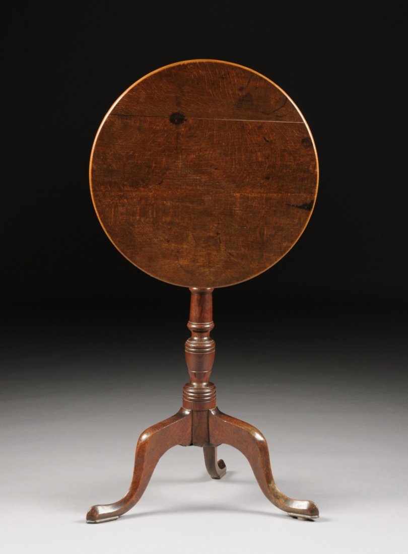 A QUEEN ANNE STYLE CARVED OAK TILT-TOP CANDLE STAND,: A QUEEN ANNE STYLE CARVED OAK TILT-TOP CANDLE STAND, PROBABLY LATE 19TH/EARLY 20TH CENTURY, the rounded top with a later brass table lock, above a turned columnar stem, raised on a tripod base of styl