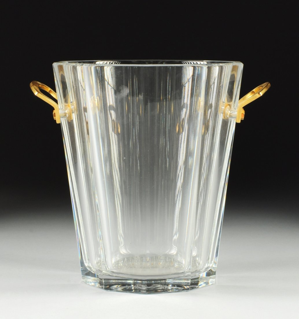 A BACCARAT CRYSTAL CHAMPAGNE COOLER, in the Maxim: A BACCARAT CRYSTAL CHAMPAGNE COOLER, in the Maxim pattern with flared paneled sides flanked by gilt metal handles. Height: 9"