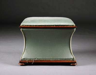 A VICTORIAN UPHOLSTERED AND CARVED WALNUT STORAGE: A VICTORIAN UPHOLSTERED AND CARVED WALNUT STORAGE OTTOMAN, LATE 19TH CENTURY, of rectangular padded form with hinged lid above in curved sides, raised on circular pad feet. Height: 17" 