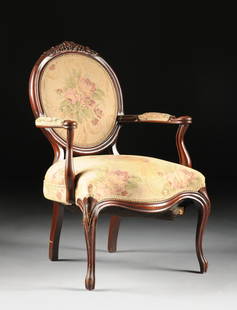 A ROCOCO REVIVAL STYLE CARVED MAHOGANY ARMCHAIR, EARLY: A ROCOCO REVIVAL STYLE CARVED MAHOGANY ARMCHAIR, EARLY 20TH CENTURY, the medallion padded back with a fruiting cluster detailed crest rail above sinuous arms on a conforming padded seat with