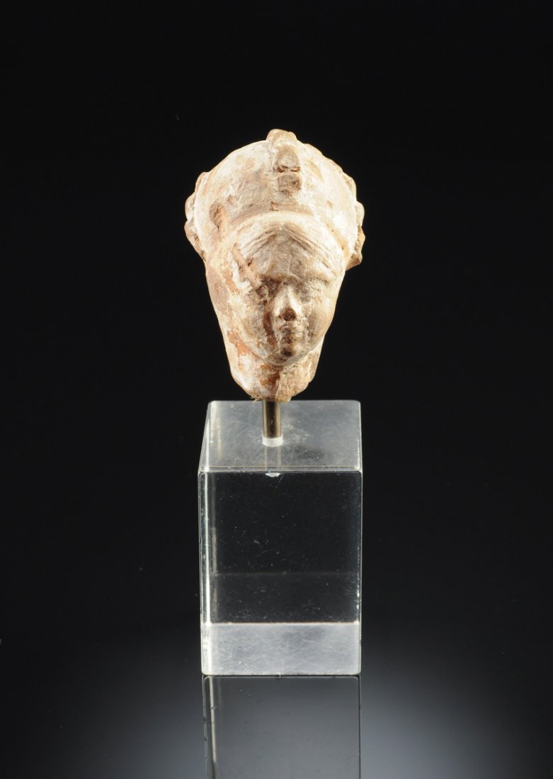 A BYZANTINE TERRACOTTA BUST OF A MAIDEN,: A BYZANTINE TERRACOTTA BUST OF A MAIDEN, with finely detailed hair and facial features beneath a stylized headdress, traces of white pigment throughout, mounted on acrylic base. Height: 1 3/4"