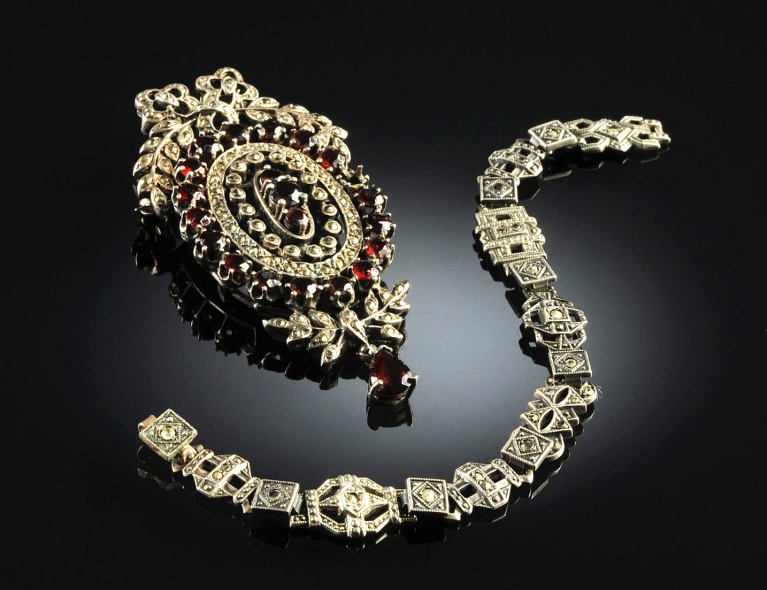 AN EDWARDIAN STYLE STERLING SILVER AND MARCASITE BRACEL: AN EDWARDIAN STYLE STERLING SILVER AND MARCASITE BRACELET WITH A STERLING, MARCASITE, AND GARNET BROOCH, EARLY 20TH CENTURY, the bracelet with intricate geometric links studded with gently faceted mar