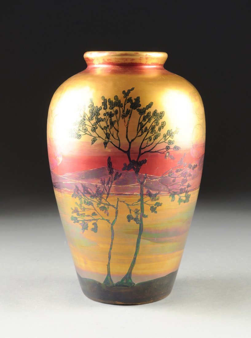 A WELLER LASA IRIDESCENT POLYCHROME PORCELAIN ART VASE,: A WELLER LASA IRIDESCENT POLYCHROME PORCELAIN ART VASE, 20TH CENTURY, the ovoid form having rich tones of red, purple, and gold, depicting a mountainous landscape over water with sparsely leafed slend
