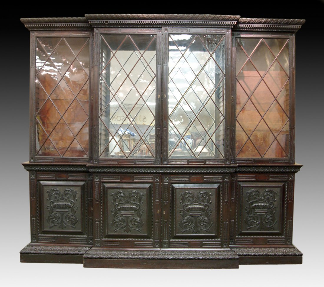 A CONTINENTAL CARVED EBONIZED WOOD BREAKFRONT CABINET,: A CONTINENTAL CARVED EBONIZED WOOD BREAKFRONT CABINET, POSSIBLY COLONIAL, LATE 18TH/EARLY 19TH CENTURY, the gadrooned and dentilated cornice above paired glazed central doors with lozenge pattern mull