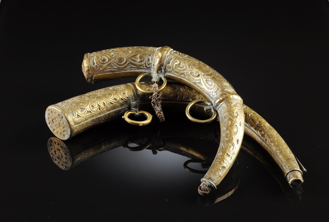 A PAIR OF ANTIQUE MOROCCAN CURVED BRASS POWDER HORNS,: A PAIR OF ANTIQUE MOROCCAN CURVED BRASS POWDER HORNS, each embossed and engraved with foliate scrolls and flower heads. Height: 16"