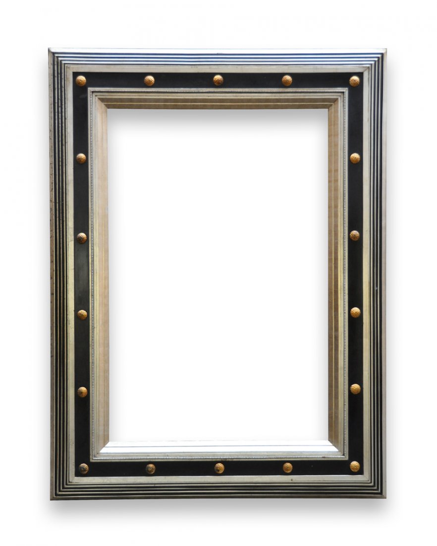 A LARGE AMERICAN ART DECO SILVER LEAF AND EBONIZED: A LARGE AMERICAN ART DECO SILVER LEAF AND EBONIZED CARVED WOOD FRAME, SECOND QUARTER 20TH CENTURY, the stepped rectangular border enclosing a conforming recessed panel centering circular parcel gilt b
