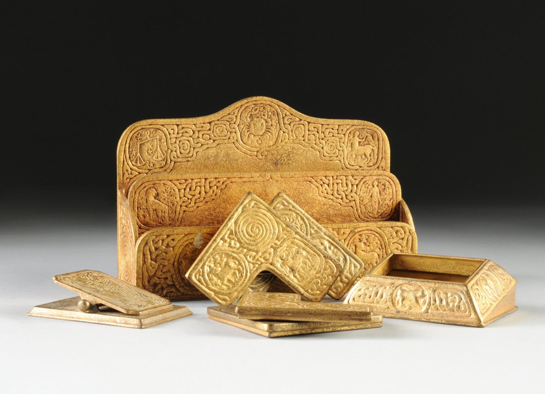 A FOUR PIECE TIFFANY STUDIOS GILT BRONZE DESK SET,: A FOUR PIECE TIFFANY STUDIOS GILT BRONZE DESK SET, ZODIAC AND CHINESE PATTERNS, EACH IMPRESSED WITH "TIFFANY STUDIOS" ABOVE "NEW YORK" AND MODEL NUMBERS, EARLY 20TH CENTURY, comprising a stepped lette