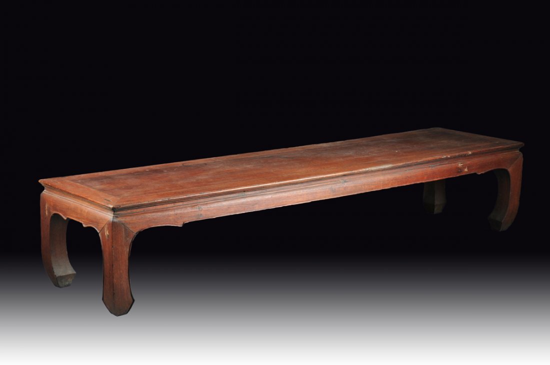 AN ANTIQUE CHINESE CARVED HARDWOOD KANG LOW TABLE, QING: AN ANTIQUE CHINESE CARVED HARDWOOD KANG LOW TABLE, QING DYNASTY, 19TH CENTURY, the long rectangular top with "ice plate" edge above a recessed flat waist over a rounded and shaped apron, raised on in-