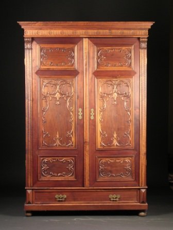 A VICTORIAN CARVED MAHOGANY ARMOIRE, THIRD QUARTER 19TH: A VICTORIAN CARVED MAHOGANY ARMOIRE, THIRD QUARTER 19TH CENTURY, the rectangular molded cornice above a carved paterae and fluted frieze, over hinged doors centering panels of "C" scrolls and swirling