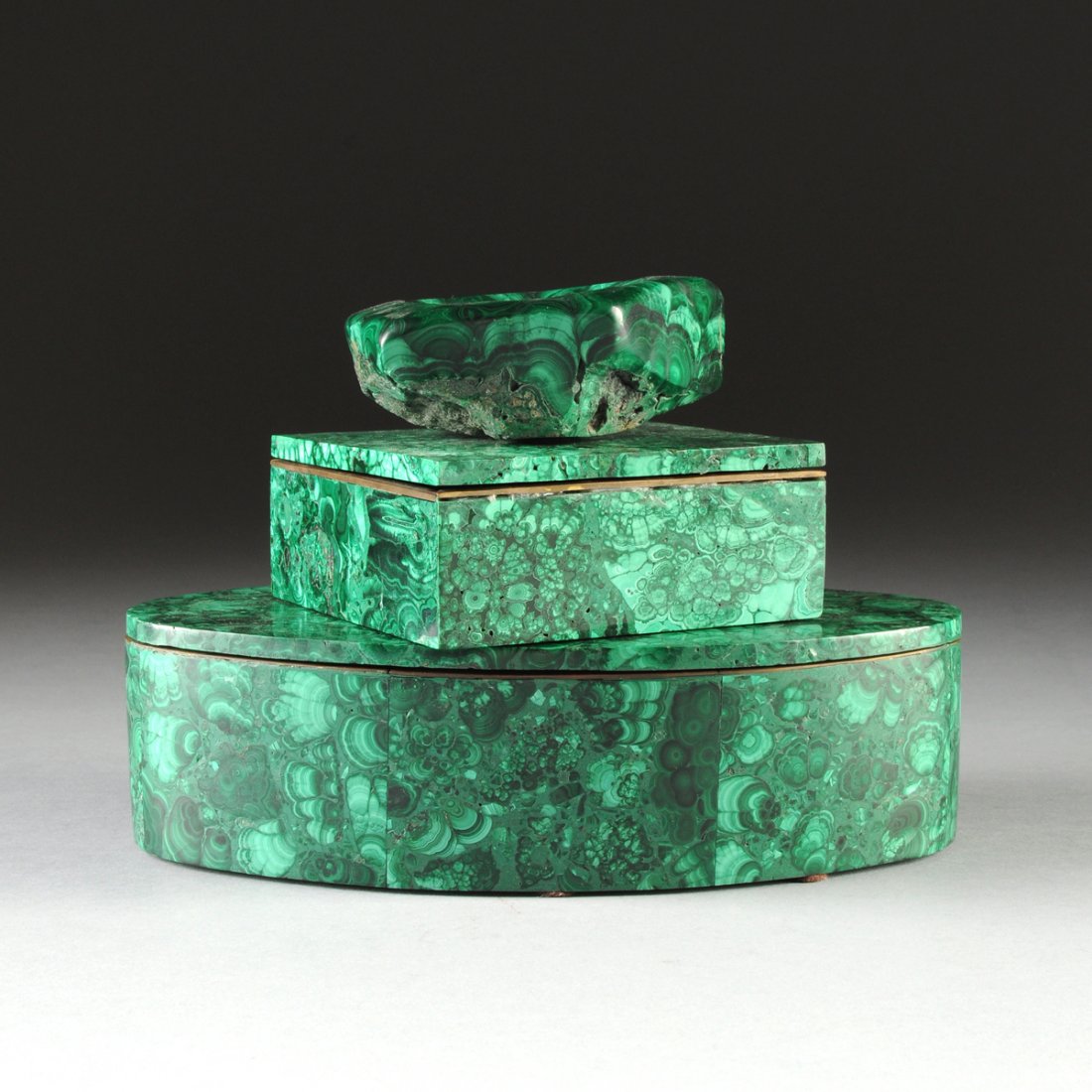 A GROUP OF THREE MALACHITE TABLE TOP ACCESSORIES,: A GROUP OF THREE MALACHITE TABLE TOP ACCESSORIES, MODERN, a flat topped oval lidded box, height: 2 3/4”, width: 6 3/4”, depth: 4”; a rectangular flat topped lidded box, height: 1 7/8", width: 4 