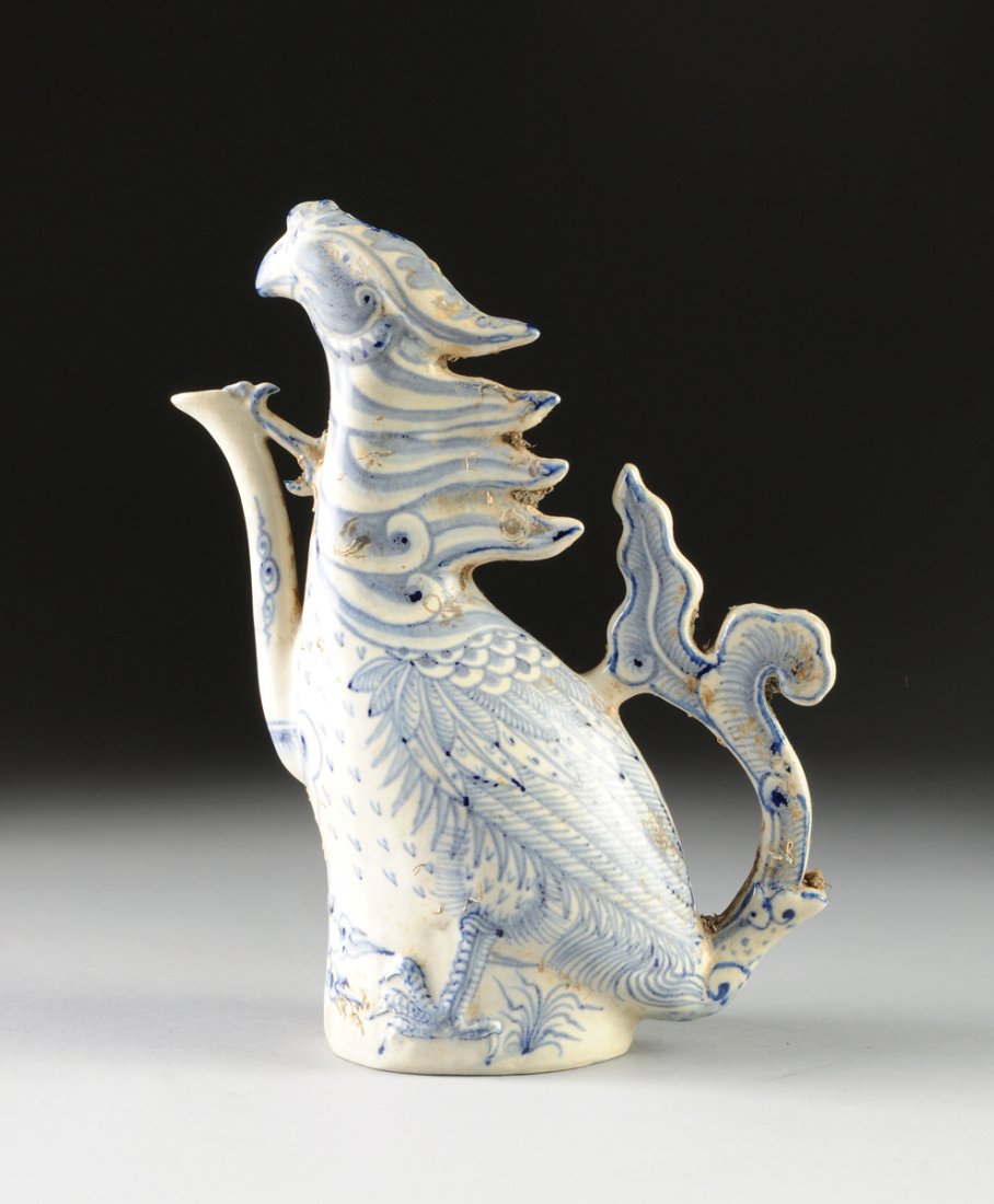 A VIETNAMESE/ ANNAMESE BLUE AND WHITE CERAMIC PHOENIX: A VIETNAMESE/ ANNAMESE BLUE AND WHITE CERAMIC PHOENIX FORM WINE EWER, 15TH/16TH CENTURY, Painted with underglaze blue details through-out and modeled as a stylized crested phoenix with a long neck iss