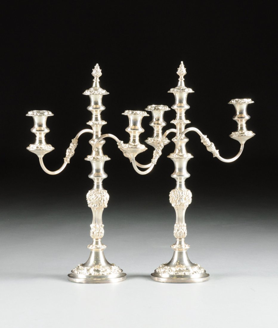 A PAIR OF GEORGE III STYLE SILVER PLATED THREE-LIGHT: A PAIR OF GEORGE III STYLE SILVER PLATED THREE-LIGHT CANDELABRA, MAKER'S MARK, ENGLISH, 20TH CENTURY, each with a shaped scrolling foliate repoussé stem beneath a vasiform nozzle fitted with a three-