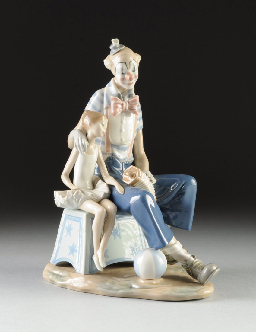 A LLADRO POLYCHROME ENAMELED FIGURAL GROUP, "AT THE: A LLADRO POLYCHROME ENAMELED FIGURAL GROUP, "AT THE CIRCUS," BLUE AND IMPRESSED MARKS, 1980'S, painted in traditional colors and modeled as a young girl and circus clown seated on a spreading rectangu