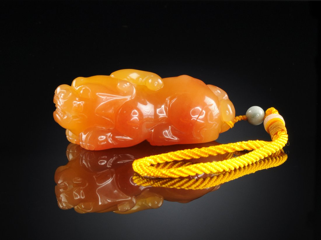 A CHINESE CARVED INDONESIAN TIANHUANG SOAPSTONE,: A CHINESE CARVED INDONESIAN TIANHUANG SOAPSTONE, RECUMBENT FIGURE OF A FOO DOG, 20TH CENTURY, the carved figure of a recumbent foo dog in natural semi-translucent red veined honey colored Indonesian T