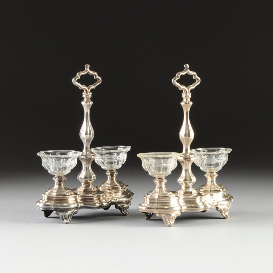 A PAIR OF CONTINENTAL CUT GLASS MOUNTED SILVER PLATED: A PAIR OF CONTINENTAL CUT GLASS MOUNTED SILVER PLATED SALT STANDS, POSSIBLY FRENCH, LATE 19TH/EARLY 20TH CENTURY, each in the Baroque style and of shaped oval form centering a conforming stem surmount
