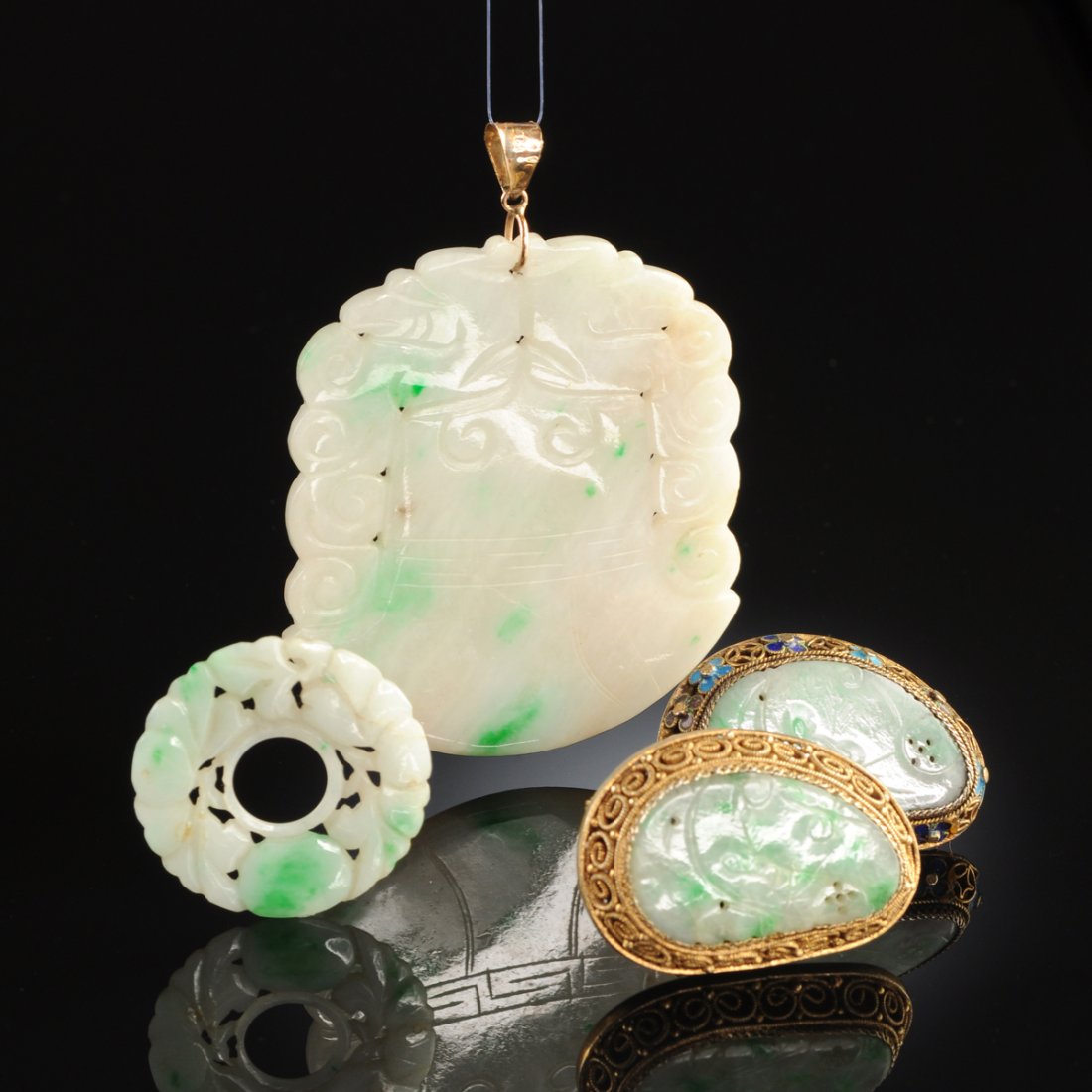 A GROUP OF FOUR CHINESE "MOSS-IN-SNOW" JADE JADEITE: A GROUP OF FOUR CHINESE "MOSS-IN-SNOW" JADE JADEITE ORNAMENTS, comprising a carved jade disk with reticulated floral and foliate carved decoration, diameter: 1 1/8"; a shaped pendant with carved bell