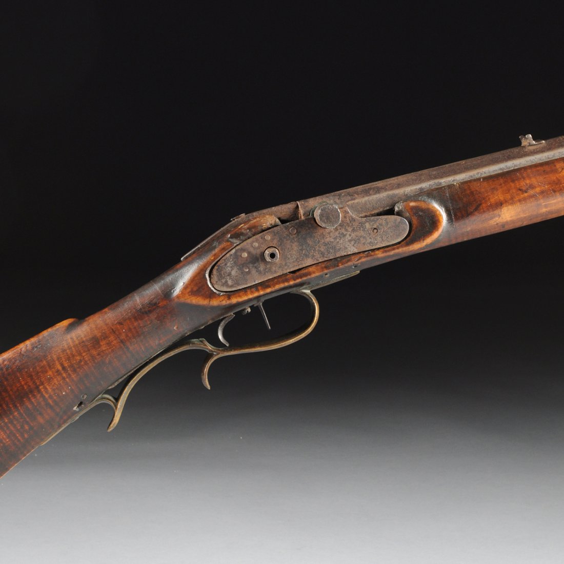 AN ANTIQUE AMERICAN RIFLE, POSSIBLY HAWKEN, ENGRAVED: AN ANTIQUE AMERICAN RIFLE, POSSIBLY HAWKEN, ENGRAVED "H," EARLY 19TH CENTURY, the octagonal barrel with a carved maple stock and slightly curving Roman nose ending in a brass capped crescent shaped bu