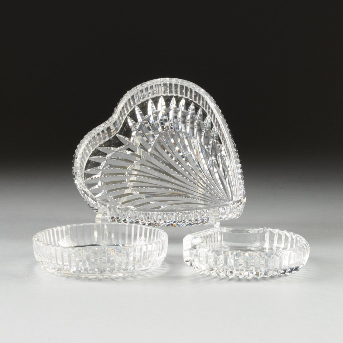 A GROUP OF THREE WATERFORD CUT CRYSTAL TABLE WARES,: A GROUP OF THREE WATERFORD CUT CRYSTAL TABLE WARES, IRELAND, LATE 20TH CENTURY, comprising a heart shaped tray with radiating cut decoration, height: 1 1/2", width: 7 3/8", depth: 7 1/2"; a shell shap