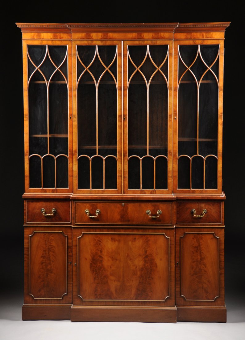 A GOTHIC REVIVAL STYLE CARVED WALNUT BREAKFRONT: A GOTHIC REVIVAL STYLE CARVED WALNUT BREAKFRONT SECRETARY CABINET BY THE TIBBENHAM FURNITURE CO., IPSWICH, ENGLAND, LATE 20TH CENTURY, the molded and dentilated crest above a plain frieze over paired 