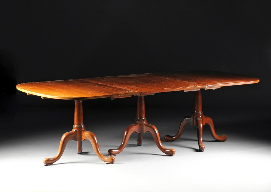 A QUEEN ANNE STYLE CARVED MAHOGANY THREE PEDESTAL: A QUEEN ANNE STYLE CARVED MAHOGANY THREE PEDESTAL DINING TABLE, BY A.F. HACKMAN, LITITZ, PENNSYLVANIA, CIRCA 1966, the rounded rectangular top with additional leaves, on columnar stems raised on tripo