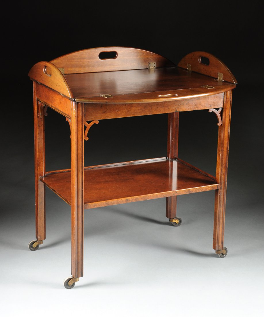 A GEORGE III STYLE MAHOGANY BUTLER'S TRAY ON STAND,: A GEORGE III STYLE MAHOGANY BUTLER'S TRAY ON STAND, the oval top with hinged flaps centering pierced handles, above reticulated arched brackets on rectangular marlborough legs connected by a shelf str