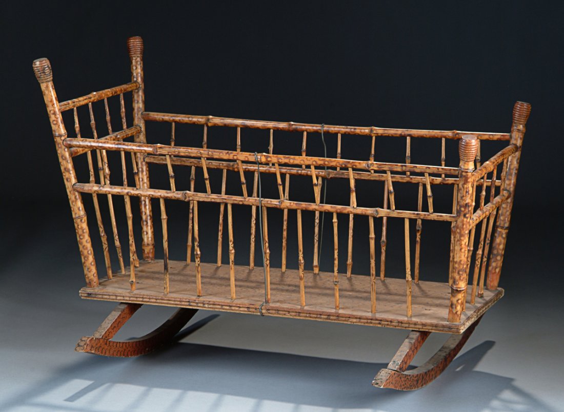 AN AMERICAN BRAND IRON DECORATED BAMBOO BABY CRADLE,: AN AMERICAN BRAND IRON DECORATED BAMBOO BABY CRADLE, the tapered rectangular form with stamp branded stylized flowers, decorated backboard, and on similarly decorated rockers. Height: 26 1/2" Width: 3