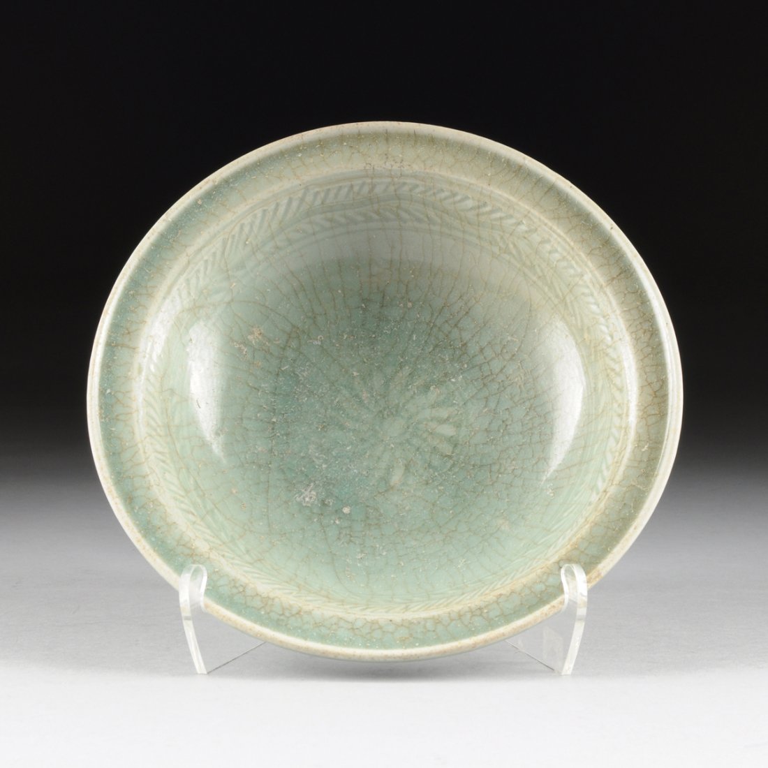 A SOUTHEAST ASIAN CELADON GLAZED EARTHENWARE BOWL WITH: A SOUTHEAST ASIAN CELADON GLAZED EARTHENWARE BOWL WITH CARVED DECORATION, POSSIBLY THAILAND, 16TH/17TH CENTURY, with celadon glaze and flattened rim, incised foliate band and lotus blossom interior, o