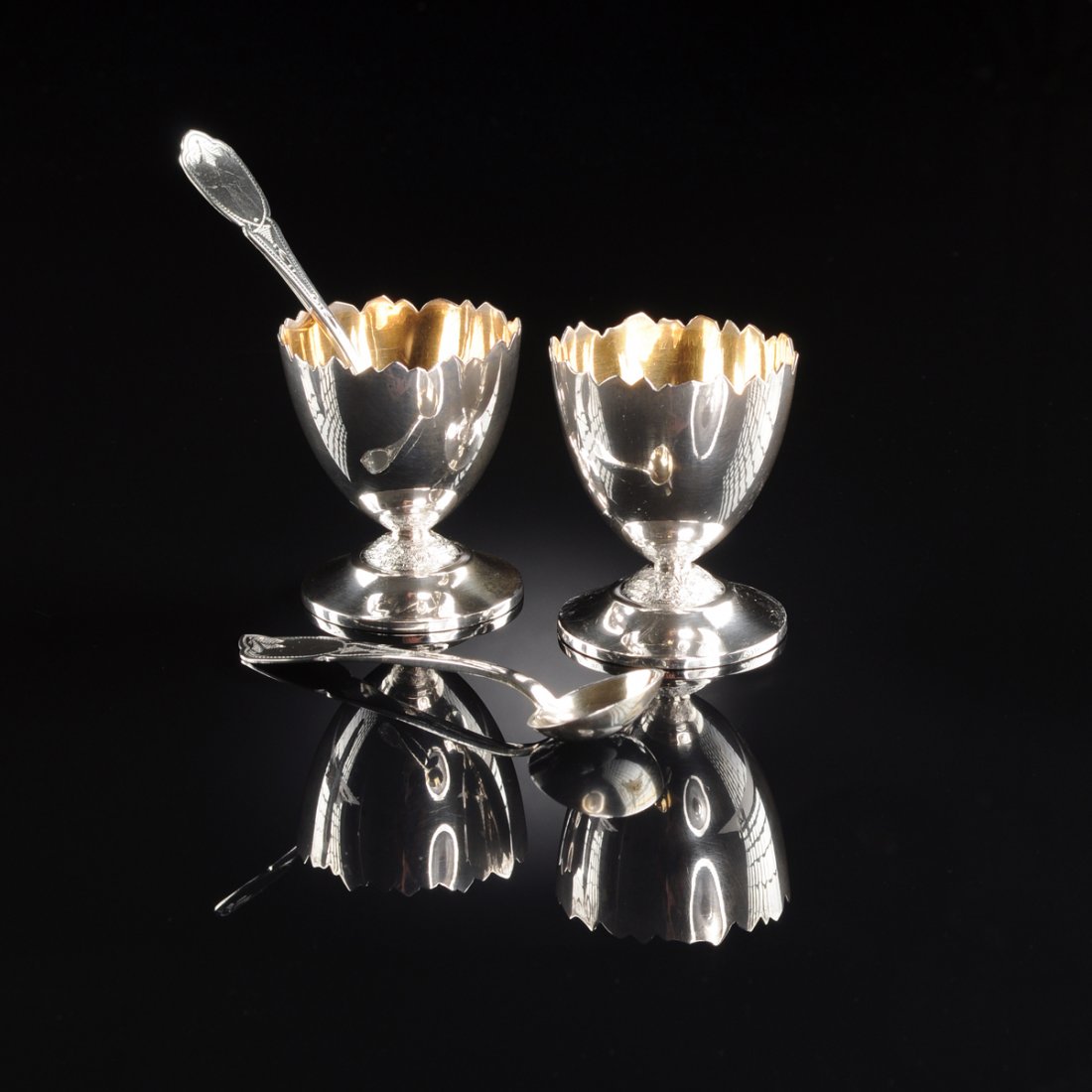 A CASED PAIR OF AMERICAN SILVER AND SILVER GILT: A CASED PAIR OF AMERICAN SILVER AND SILVER GILT FIGURAL SALTS AND SPOONS, CIRCA 1870, each in the form of a cracked hard boiled egg with jagged rim, on rockwork base and spreading conforming foot, gil