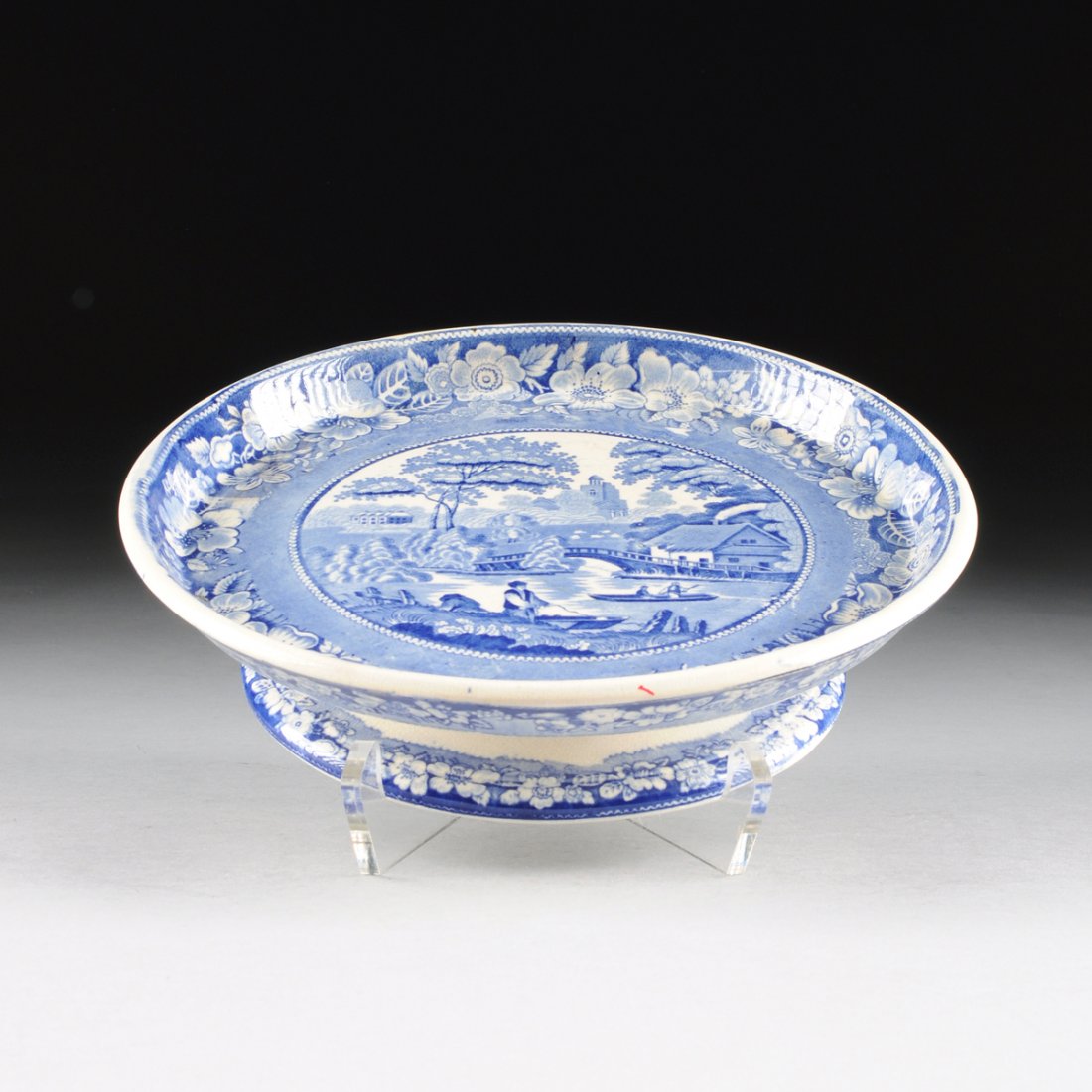 A J.F. WILEMAN BLUE AND WHITE TRANSFER PRINT POTTERY: A J.F. WILEMAN BLUE AND WHITE TRANSFER PRINT POTTERY CAKE STAND, "WILD ROSE" PATTERN, FENTON, STAFFORDSHIRE, ENGLAND, CIRCA 1869-1892, the cake stand with with raised lip to the top, raised on spreadi