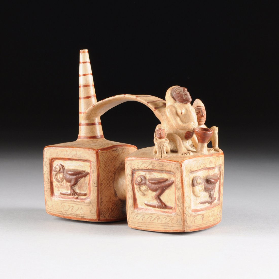 A PRE-COLUMBIAN RED AND WHITE PAINTED POTTERY WHISTLE,: A PRE-COLUMBIAN RED AND WHITE PAINTED POTTERY WHISTLE, POSSIBLY SICAN, NORTHERN PERU, 800-1000 A.D., modeled as a pair of square form blocks joined by a short cylinder, with each side depicting a prof