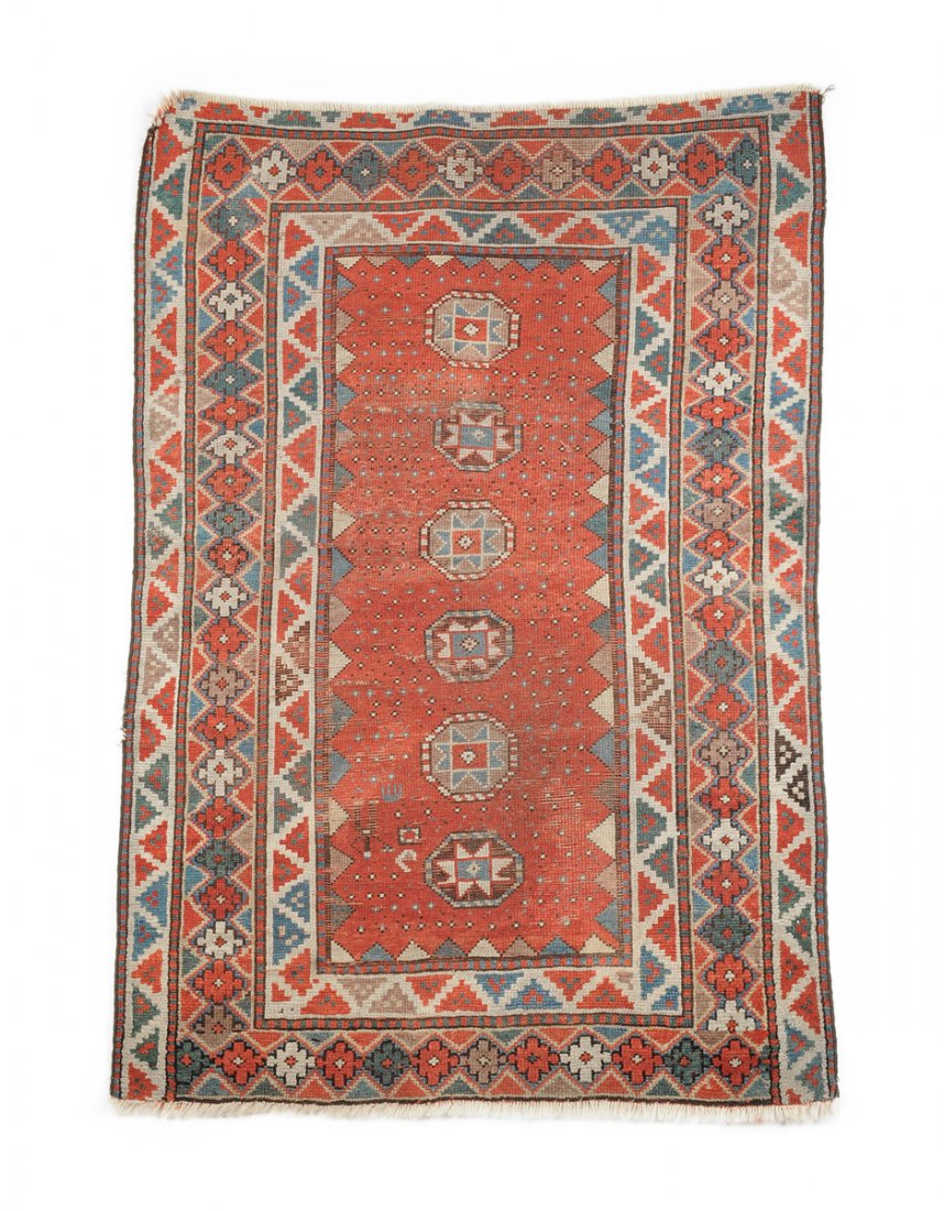 AN ANTIQUE CAUCASIAN PRAYER RUG,: AN ANTIQUE CAUCASIAN PRAYER RUG, with a rust red field and a central panel centering six stylized stars within an octagonal shield, enclosed by bands bands of red, blue and dark green stepped pyramida
