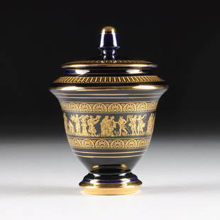 A NEOCLASSICAL STYLE PARCEL GILT COBALT BLUE LIDDED: A NEOCLASSICAL STYLE PARCEL GILT COBALT BLUE LIDDED URN, GREEK, GILT MARKS, MODERN, of tapering circular form with sides centering a continuous frieze of gilt stenciled classical figures at various pu