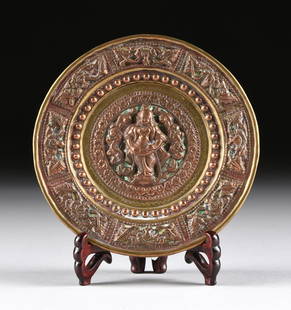 A SOUTH EAST ASIAN SMALL REPOUSSE COPPER AND BRASS: A SOUTH EAST ASIAN SMALL REPOUSSE COPPER AND BRASS OFFERINGS DISH, 20TH CENTURY, of circular form and centering a standing figure of Guanyin wearing traditional long robes, within scrolling leafy