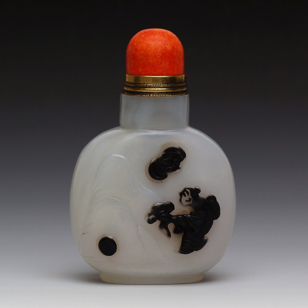 CHINESE CAMEO CARVED AGATE SNUFF BOTTLE: Chinese finely hollowed, cameo carved agate snuff bottle; of flattened circular form; the front with design of figure and ruyi fungus in relief, ; good use of color; red coral stopper; H: 3.31’’, 