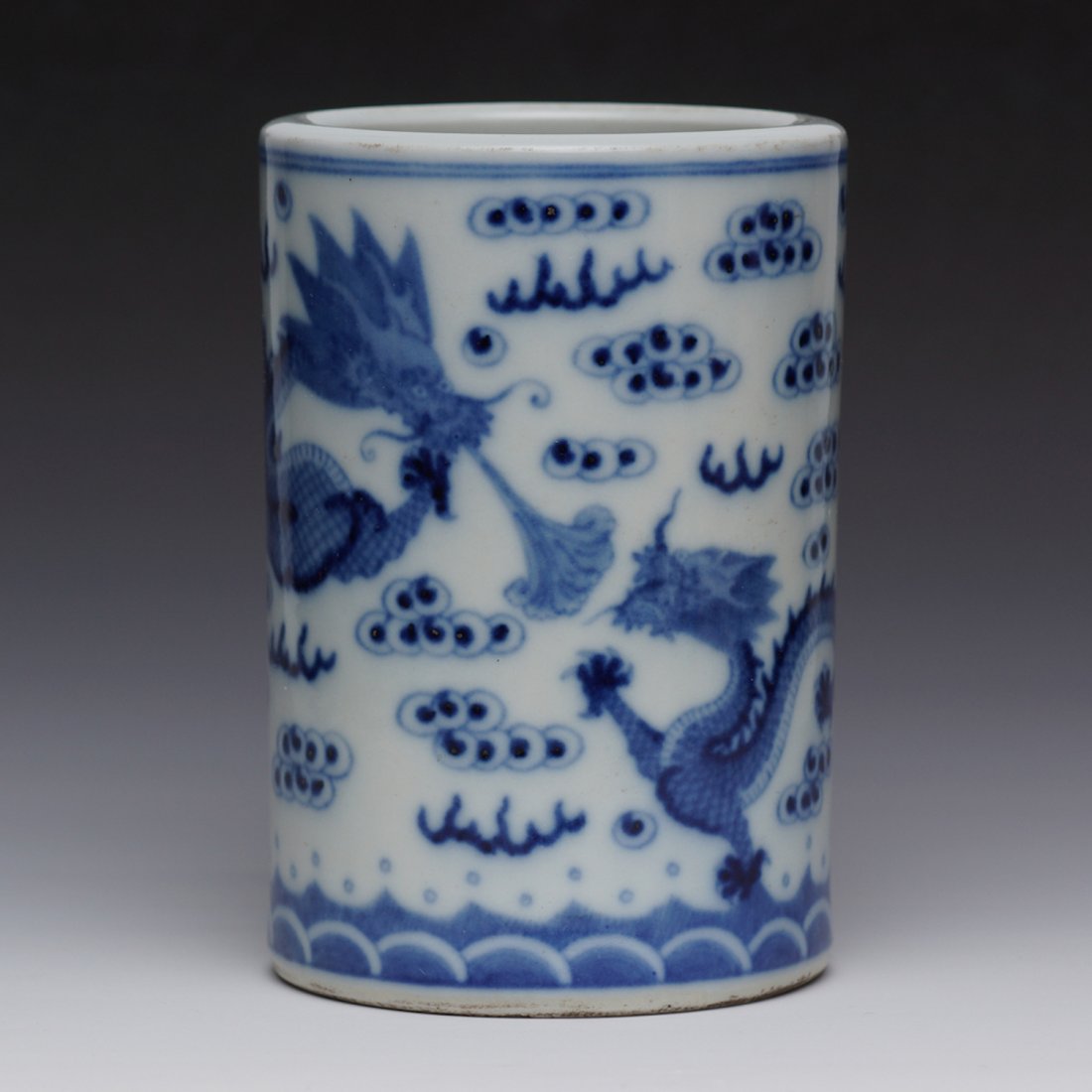 CHINESE BLUE AND WHITE PORCELAIN BRUSH POT: Chinese hand painted blue and white porcelain brush pot, Decorated with Dragon amidst flaming clouds scrolls on the exterior wall. Bottom holds six character blue calligraphy mark: Da Qing Xian Feng N