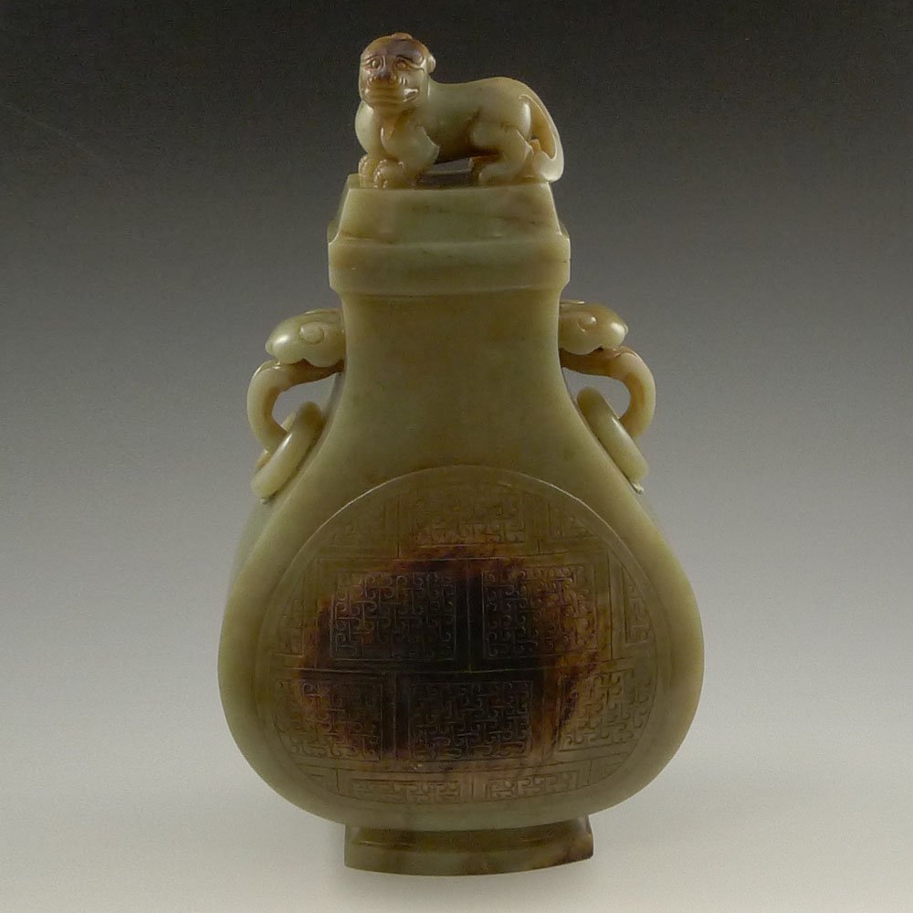 LARGE CHINESE CARVED JADE URN: Large and well carved, Chinese jade urn and cover; of somewhat archaistic bronze form, with ruyi handles pending loose rings, and with crouching qilin to cover; the stone with natural skin. Size: 10.5