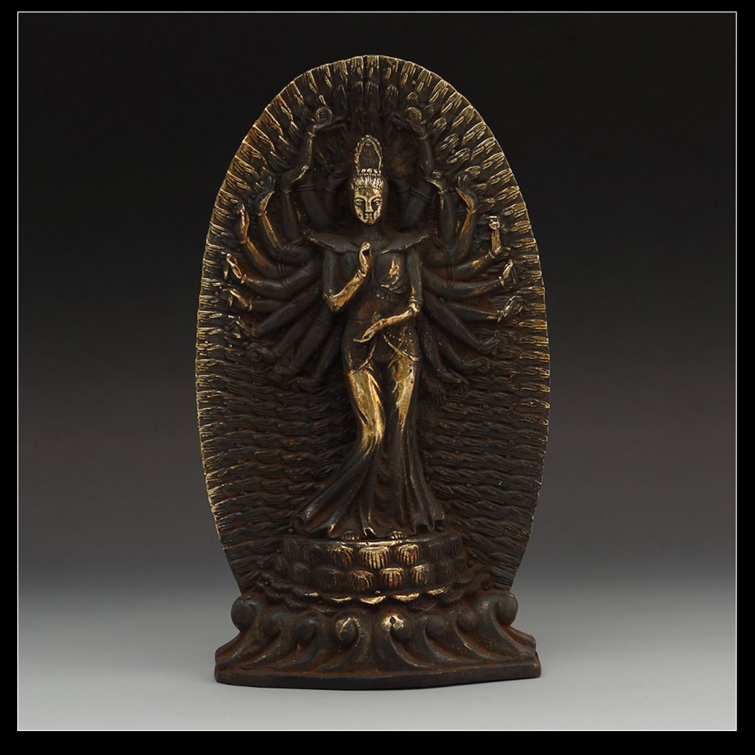 CHINESE GILT BRONZE BUDDHIST DEITY: Well cast, vintage Chinese gilt bronze multi-armed Buddhist deity; standing on a lotus pedestal and holding ritual items in each hand, with large mandorla behind. H: 7 "