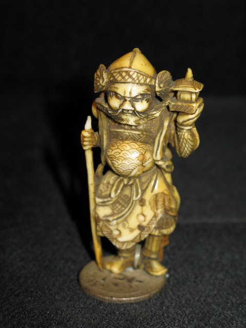 INTRICATELY CARVED IVORY NETSUKE, OLD SAMURAI: INTRICATELY CARVED IVORY NETSUKE, OLD SAMURAI HOLDING A CANE AND A LIGHT. VERY FINE DETAIL. MOUNTED ON A COIN TO SUPPORT THE STANDING FIGURE. APP. 2 1/2"H.