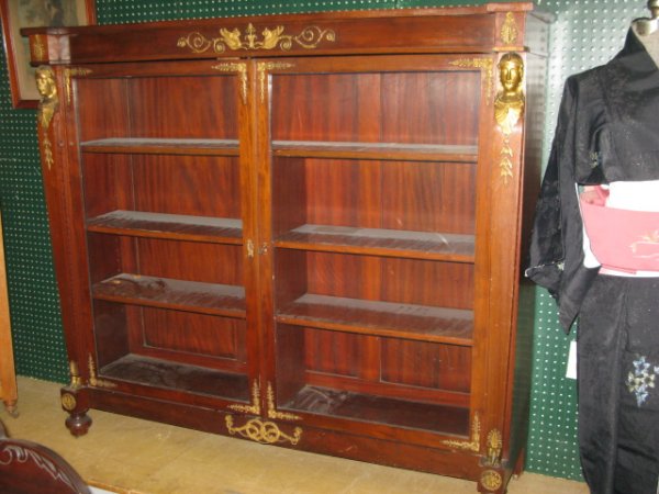 FRENCH EMPIRE MAHOGANY BOOKCASE, ORMOLU MOUNTS: FRENCH EMPIRE MAHOGANY BOOKCASE,ORMOLU MOUNTS AT SIDES OF EACH DOOR. BRASS SWAGS. ORIGINAL GLASS. MINOR SCRATCHES AT TOP OF BOOKCASE WHERE FRENCH CLOCK WAS STANDING. THIS BOOKCASE BELONGED TO SPERRY F