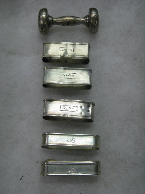 6 PCS. STERLING, 5 NAPKIN RINGS, BABY RATTLE: 6 PCS. STERLING, 5 NAPKIN RINGS WITH NAMES ETCHED (APP. 2"L). (ALL HAVE DENTS) AND A BABY RATTLE, (APP. 2 1/2"L) ALSO HAS DENTS.