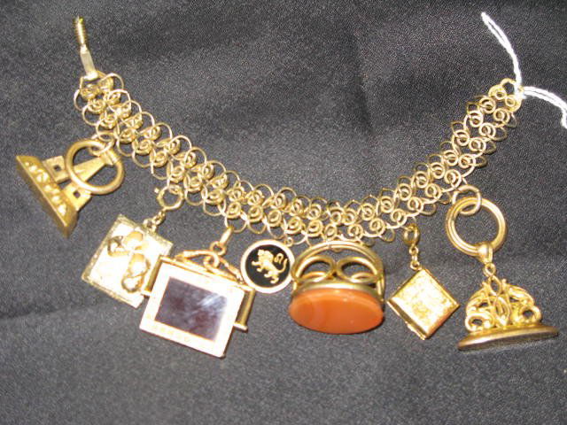 CHARM BRACELET WITH FILIGREE, VARIOUS CHARMS: CHARM BRACELET WITH FILIGREE. THERE ARE TWO 14KT. CHARMS (LION)INTAGLIO, ONE PC. 10KT. W/LARGE CARNELIAN; LG. PC. QUARTZ.