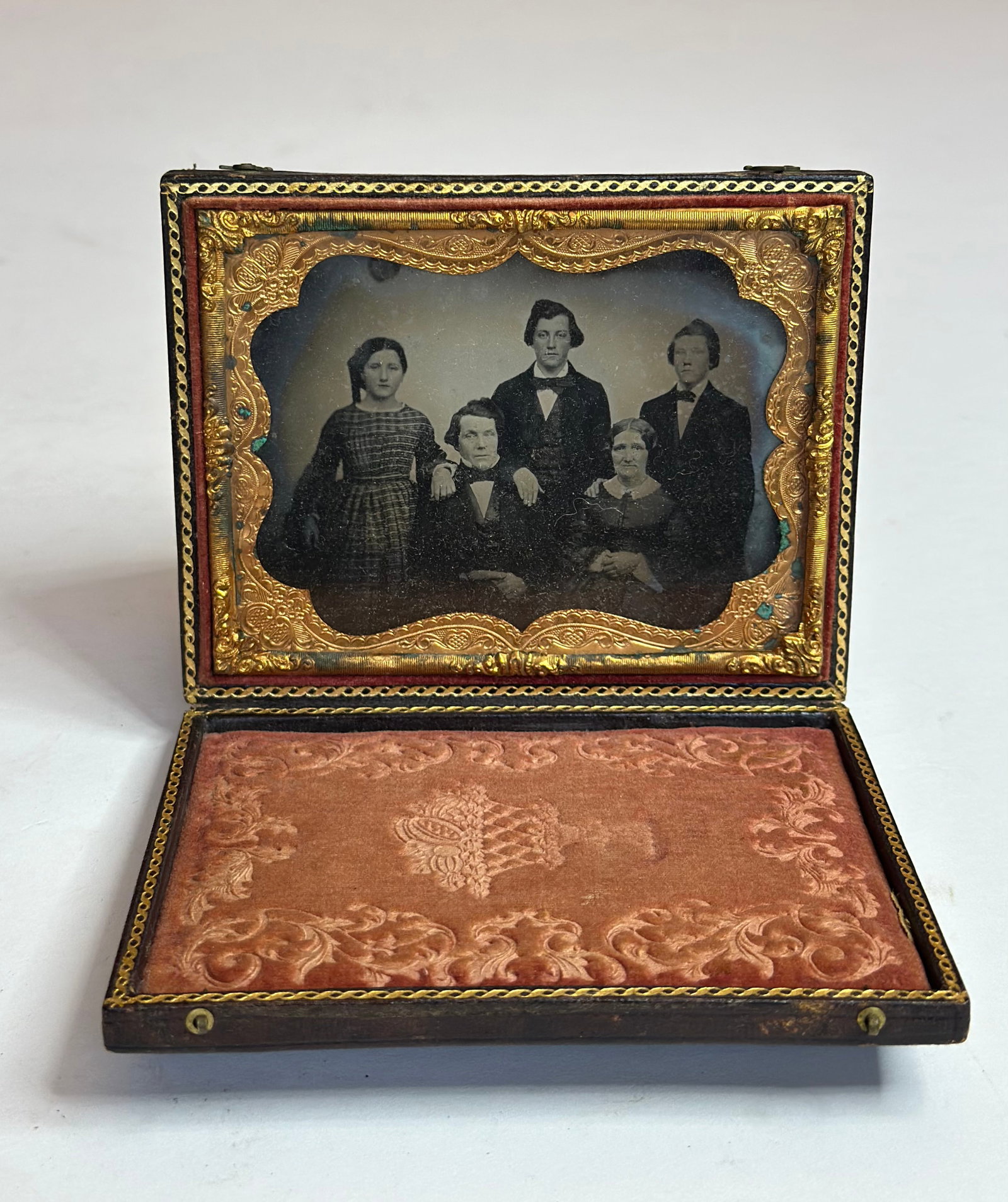 Antique Victorian Daguerreotype Family Portrait of Five in Union Case: Antique Victorian daguerreotype featuring a family portrait of five figures, housed in a molded Union case with ornate scroll and cartouche design. The image presents a seated couple with three standi