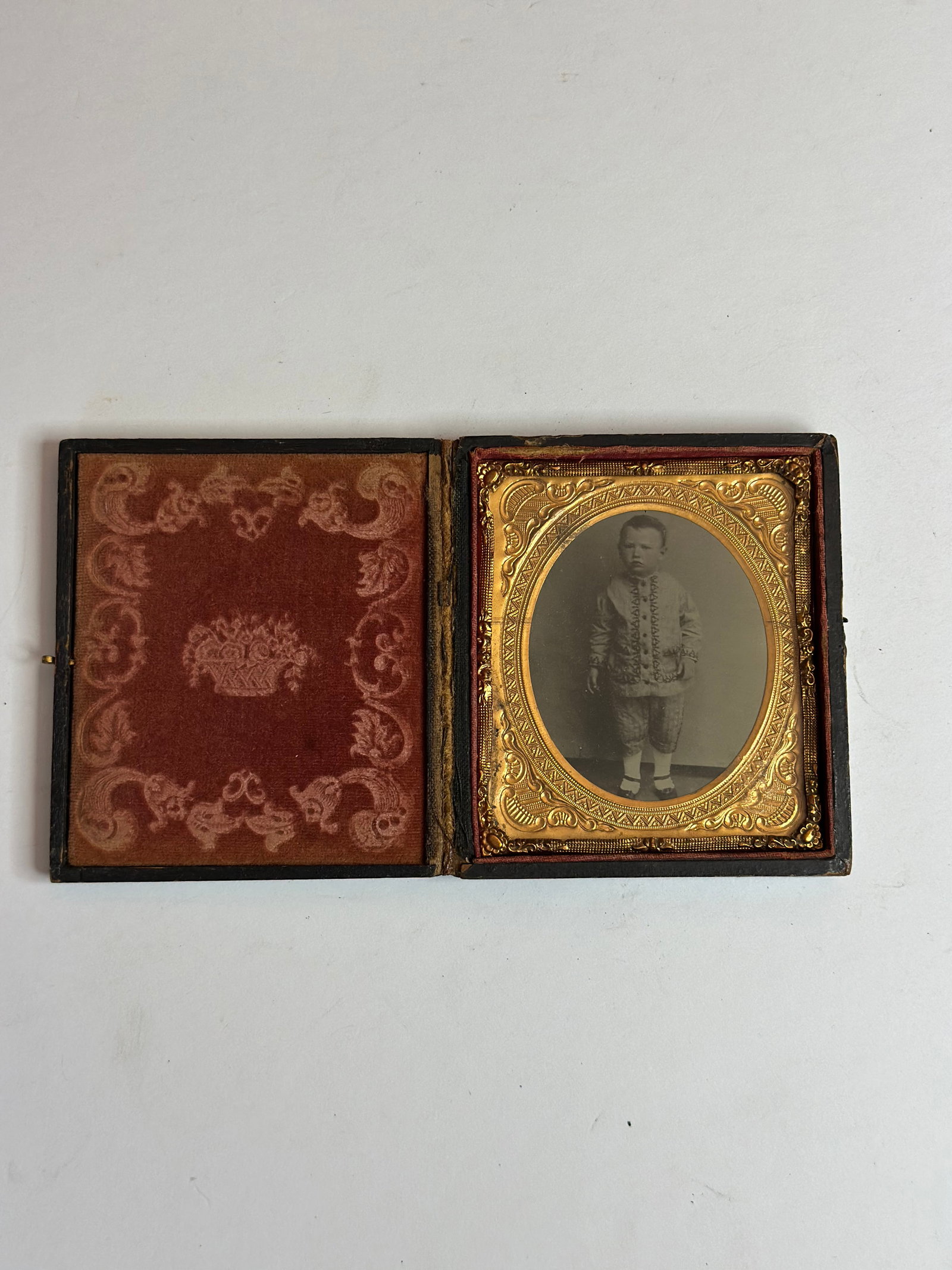 Antique Victorian Daguerreotype Portrait of Child in Union Case: Antique Victorian daguerreotype portrait of a young child, housed in a molded Union case with ornate foliate design. The image shows a standing child in period clothing, presented behind a decorative