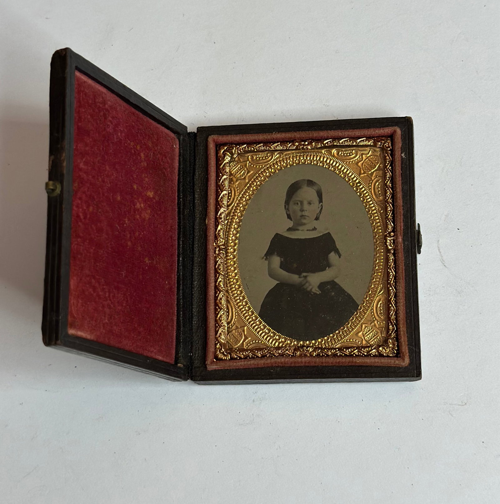 Antique Victorian Daguerreotype Portrait of Young Girl in Union Case: Antique Victorian daguerreotype portrait of a young girl, housed in a molded Union case with foliate and oval cartouche design. The image shows a seated child in dark dress with white collar, presente